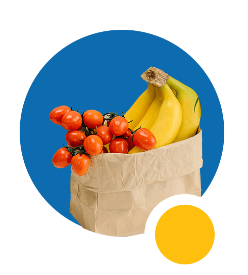 Bananas and tomatoes inside a brown paper bag. 
