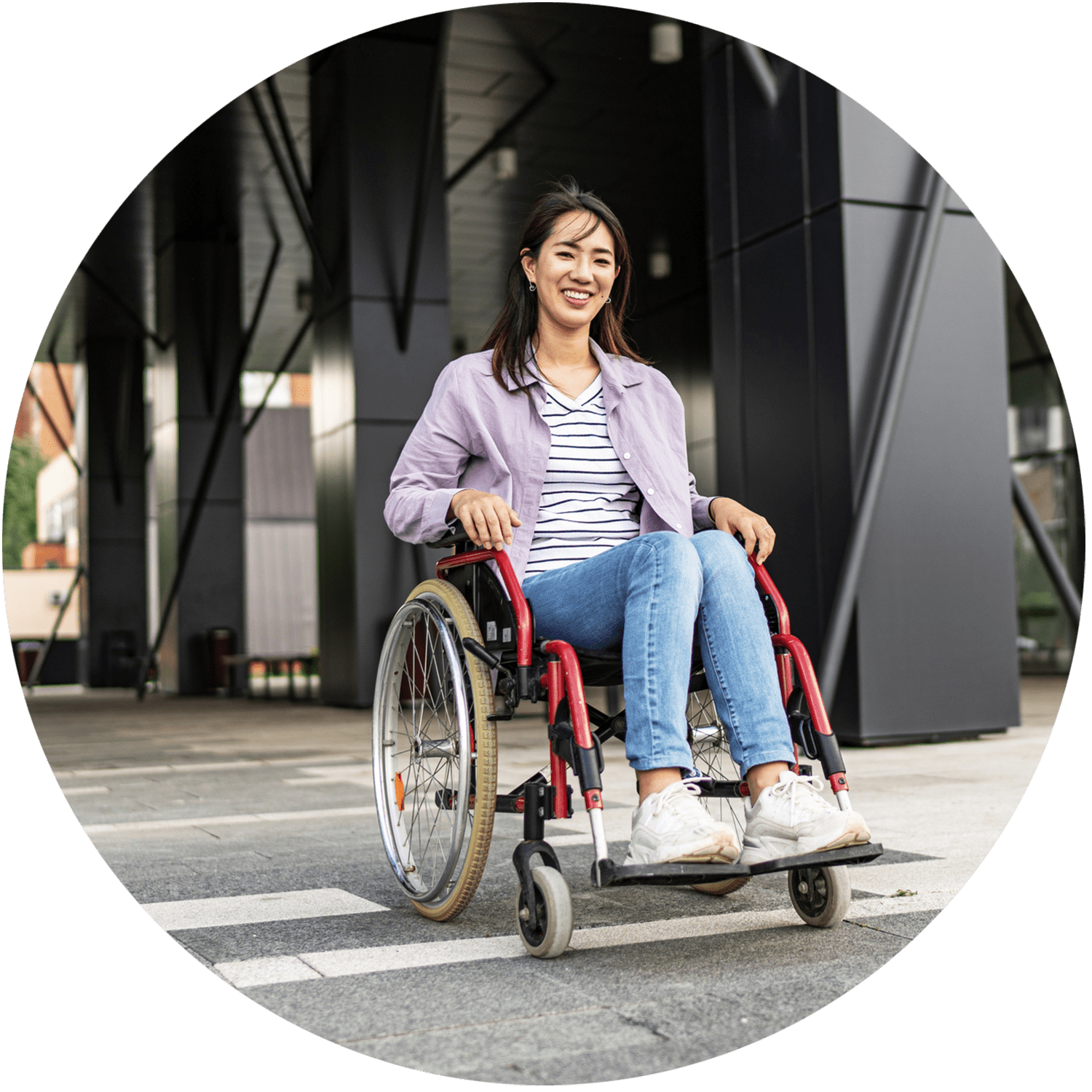 A smiling student in a wheelchair outside a building.